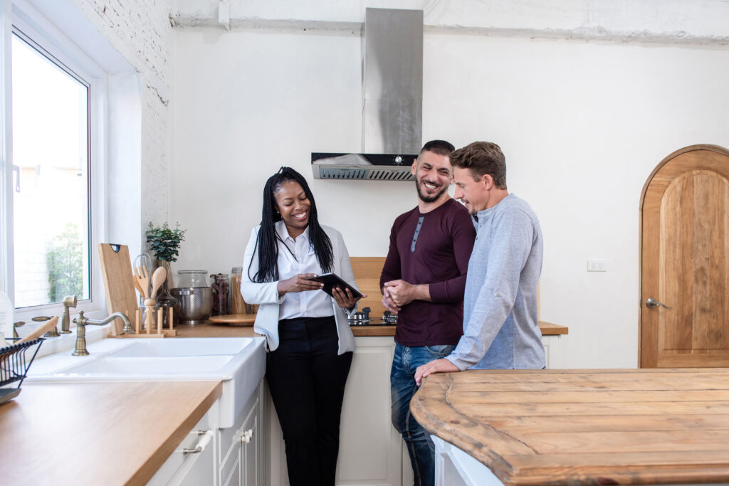 two men laugh with real estate agent while attending an open house - how to hire a buyer's agent