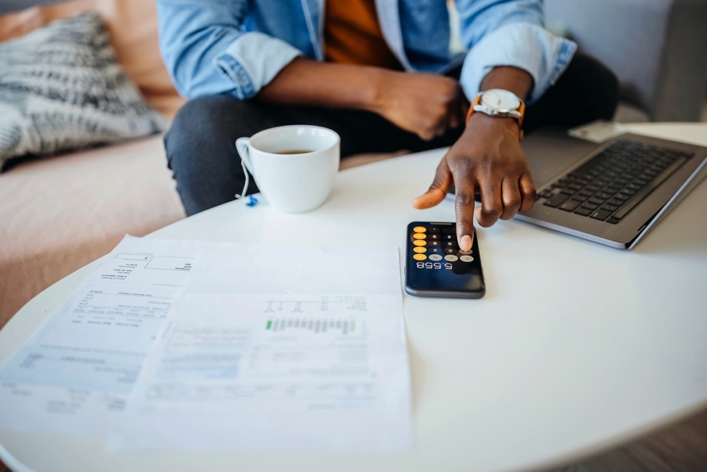 man with calculator, papers, and cup of tea - how to make a winning offer on an NYC home