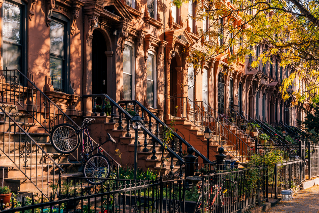 row of sunlit brownstones in Park Slope, Brooklyn with yellow tree — fall in New York