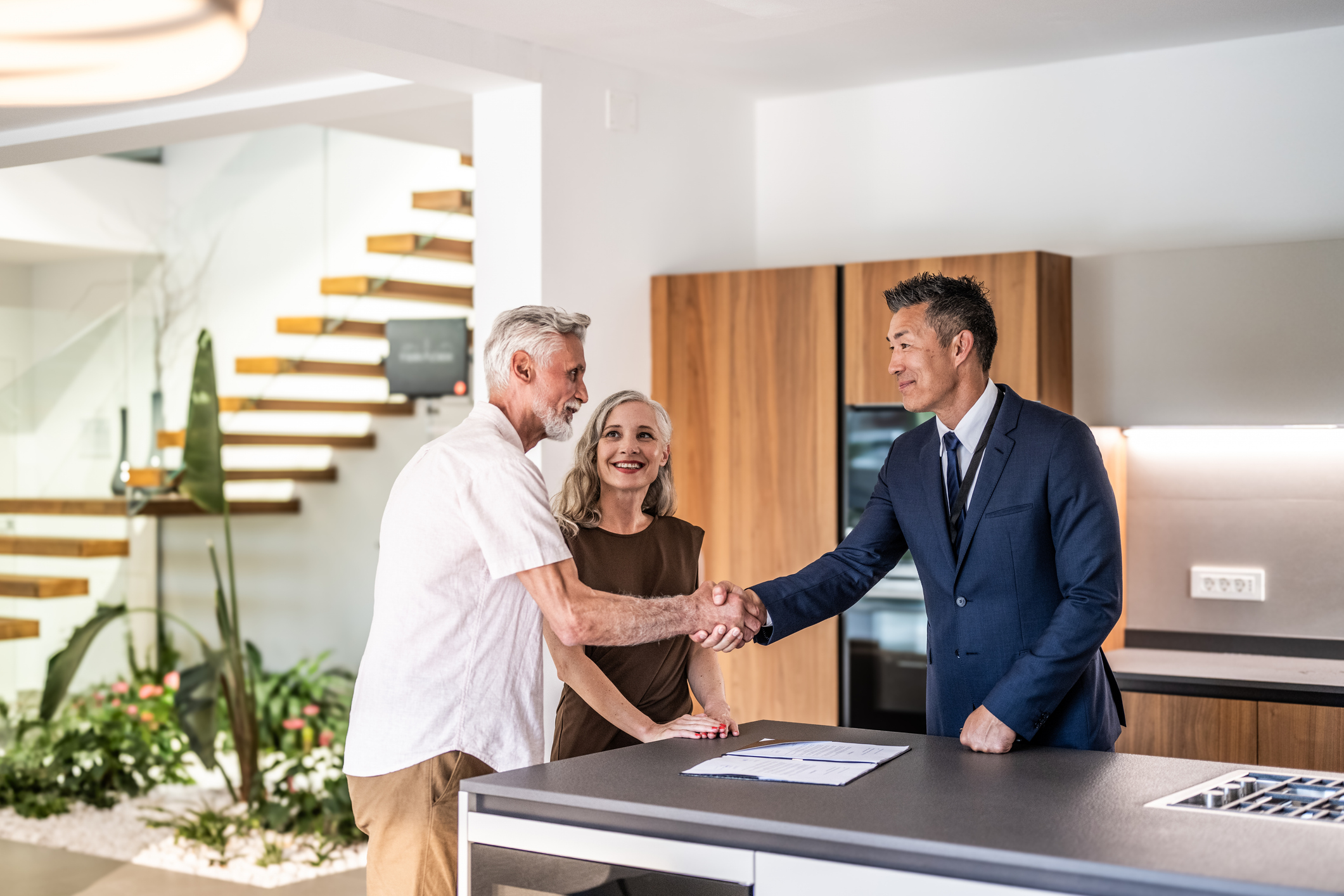 couple shaking hands with real estate agent - how to hire buyer's agent