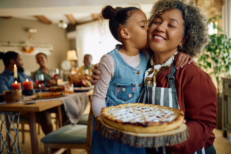 little girl kisses woman holding pie at Thanksgiving - pie in NYC