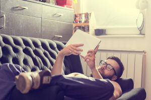 photo of man on couch reading tablet